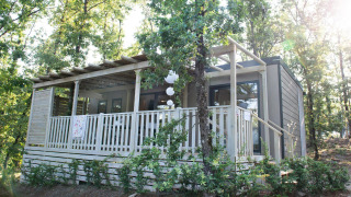 Vue extérieure du lodge Next XL Superiore avec terrasse en bois, style moderne et arbres environnants.