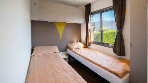 Habitación con dos camas individuales y ventana con vistas a las montañas en «Next XL» Superiore, Chianti Glamping Resort, Italia.
