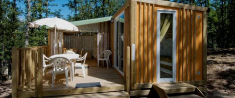 Buitenaanzicht van Cottage Clever-lodge bij Chianti Glamping Resort in Italië, met terras tussen bomen.