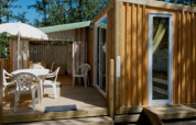 Außenansicht der Cottage Clever Lodge im Chianti Glamping Resort, Italien, mit Terrasse im Grünen.
