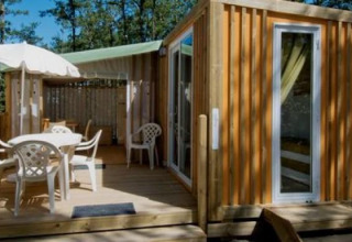 Buitenaanzicht van Cottage Clever-lodge bij Chianti Glamping Resort in Italië, met terras tussen bomen.