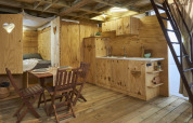 Interior of Airlodge 2.0 featuring wood paneling, compact kitchen, dining area, and loft ladder.