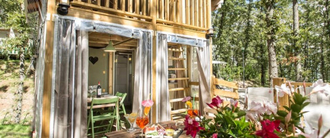 Airlodge 1 at Chianti Glamping Resort in Italy, outdoor dining and seating area surrounded by lush trees.