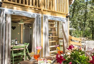 Airlodge 1 at Chianti Glamping Resort in Italy, outdoor dining and seating area surrounded by lush trees.