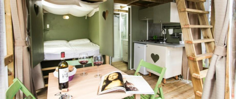 Cozy interior of Airlodge 1 at Chianti Glamping Resort in Italy with dining table, bed, and kitchenette.