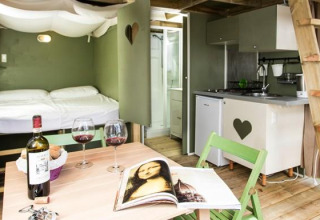 Cozy interior of Airlodge 1 at Chianti Glamping Resort in Italy with dining table, bed, and kitchenette.