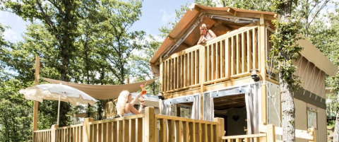 Two women relax on the terrace and balcony of Airlodge 1 at Chianti Glamping Resort, surrounded by forest.