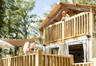 Two women relax on the terrace and balcony of Airlodge 1 at Chianti Glamping Resort, surrounded by forest.