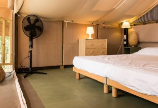 Bedroom with double bed, wooden furniture, lamps, and fan at Airlodge 1, Chianti Glamping Resort, Italy.