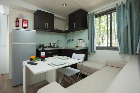 Moderne Küche und Essbereich im Cottage Next des Chianti Glamping Resort, mit Sofa und großem Fenster.
