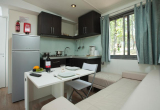 Moderne Küche und Essbereich im Cottage Next des Chianti Glamping Resort, mit Sofa und großem Fenster.