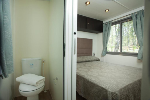 Ein Schlafzimmer und ein kleines Badezimmer in einer Cottage Next-Unterkunft im Chianti Glamping Resort in Italien.