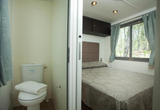 Ein Schlafzimmer und ein kleines Badezimmer in einer Cottage Next-Unterkunft im Chianti Glamping Resort in Italien.