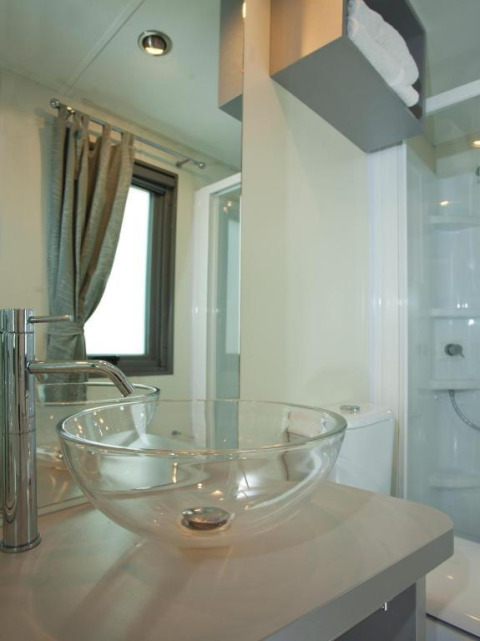 Modernes Badezimmer mit Glaswaschbecken und Spiegel im Cottage Next im Chianti Glamping Resort, Italien.