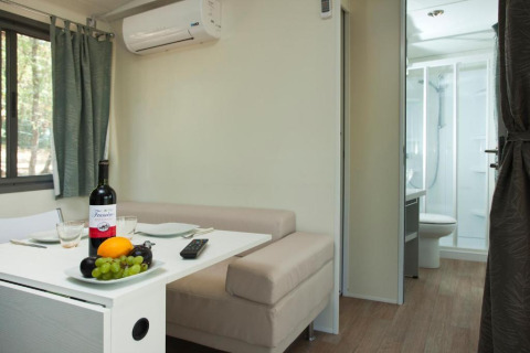 Moderner Wohnbereich im Cottage Next des Chianti Glamping Resort mit Tisch, Sofa und Badezimmer im Blick.