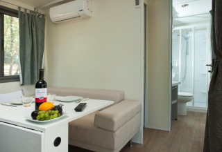 Moderner Wohnbereich im Cottage Next des Chianti Glamping Resort mit Tisch, Sofa und Badezimmer im Blick.