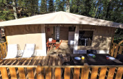 Außenterrasse mit Esstisch, Stühlen und Liegestühlen vor einem Lodge-Zelt im Chianti Glamping Resort, Italien.