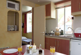 Vista interior de cocina y comedor en el lodge Cottage Classic, Chianti Glamping Resort, Italia.