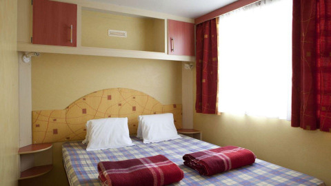 Chambre du Cottage Classic au Chianti Glamping Resort en Italie avec lit double et couvertures rouges.