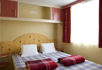 Chambre du Cottage Classic au Chianti Glamping Resort en Italie avec lit double et couvertures rouges.