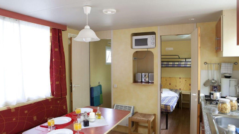 Intérieur du lodge Cottage Classic au Chianti Glamping Resort en Italie, avec table à manger et lits superposés.