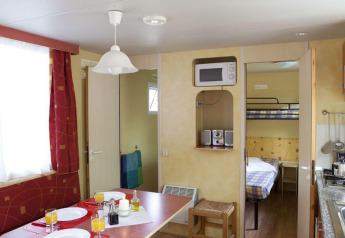 Interno del Cottage Classic presso il Chianti Glamping Resort in Italia, con tavolo da pranzo e letti a castello.