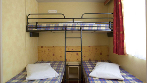 Chambre du Cottage Classic au Chianti Glamping Resort avec lits superposés et literie à carreaux.