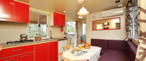 Cuisine lumineuse et coin repas avec armoires rouges au Cottage Classic, Chianti Glamping Resort, Italie.