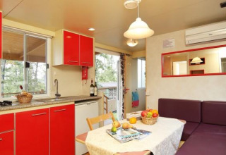 Cuisine lumineuse et coin repas avec armoires rouges au Cottage Classic, Chianti Glamping Resort, Italie.