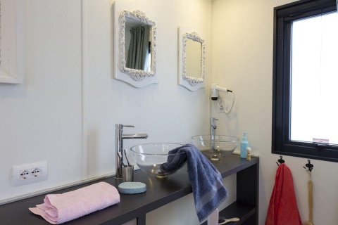 Moderne badkamer met twee glazen waskommen, witte spiegels en handdoeken in de Cube Suite, Chianti Glamping.