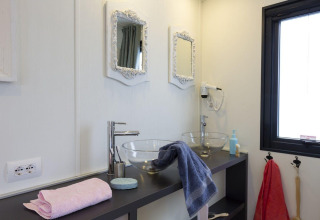Moderne badkamer met twee glazen waskommen, witte spiegels en handdoeken in de Cube Suite, Chianti Glamping.