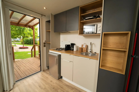 Moderne kitchenette in de Cube Suite XL van Lago Idro Glamping Boutique, met zicht op terras en tuin.