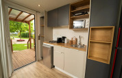 Moderne kitchenette in de Cube Suite XL van Lago Idro Glamping Boutique, met zicht op terras en tuin.