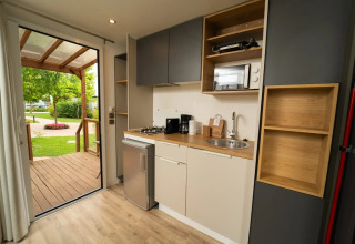 Moderne kitchenette in de Cube Suite XL van Lago Idro Glamping Boutique, met zicht op terras en tuin.