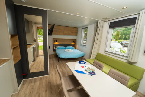 Interieur van Cube Suite XL chalet bij Lago Idro Glamping Boutique met bed, zithoek en grote ramen.