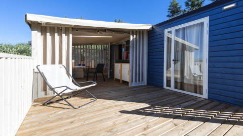 Holzterrasse des Cottage Clever bei Lago Idro Glamping Boutique in Italien mit Stuhl und Überdachung.