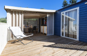 Houten terras bij Cottage Clever aan Lago Idro Glamping Boutique in Italië met stoel en schaduw.