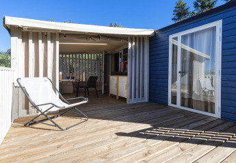 Terraza de madera en Cottage Clever en Lago Idro Glamping Boutique en Italia con silla y sombra.