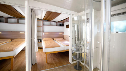 Innenansicht vom Cottage Clever Chalet im Lago Idro Glamping Boutique, Italien, mit zwei Betten und Bad.