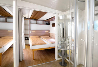 Innenansicht vom Cottage Clever Chalet im Lago Idro Glamping Boutique, Italien, mit zwei Betten und Bad.