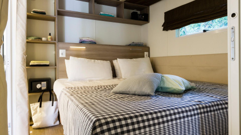 Gemütliches Schlafzimmer im Cottage Clever im Lago Idro Glamping Boutique, Italien, mit Doppelbett und Regalen.