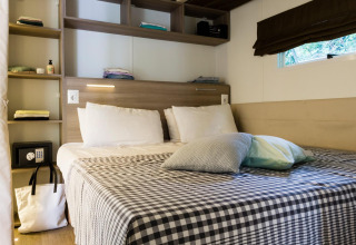 Gemütliches Schlafzimmer im Cottage Clever im Lago Idro Glamping Boutique, Italien, mit Doppelbett und Regalen.