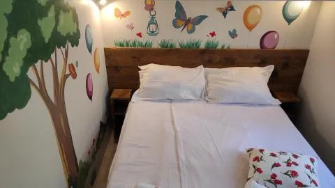 Habitación acogedora en un lodge con cama doble y murales de árbol, globos y mariposas en la pared.