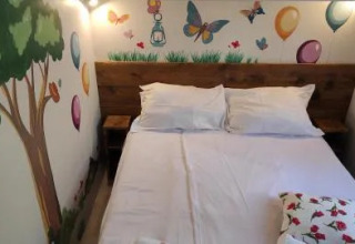 Camera accogliente in un lodge con letto matrimoniale e murales di albero, palloncini e farfalle.