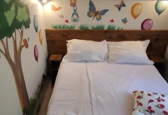 Habitación acogedora en un lodge con cama doble y murales de árbol, globos y mariposas en la pared.