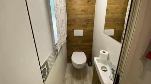 Baño moderno en la Cottage Spotty del Chianti Glamping Resort, con pared de madera, inodoro y pequeño lavabo.