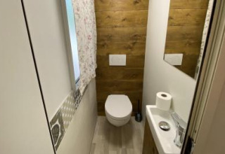 Baño moderno en la Cottage Spotty del Chianti Glamping Resort, con pared de madera, inodoro y pequeño lavabo.