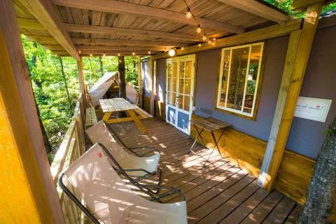 Accogliente veranda in legno a Cottage Spotty presso Chianti Glamping Resort in Italia con sedie e luci decorative.