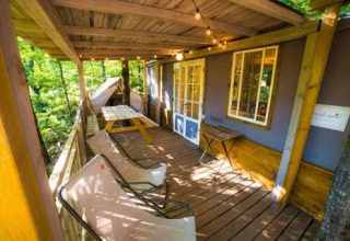 Accogliente veranda in legno a Cottage Spotty presso Chianti Glamping Resort in Italia con sedie e luci decorative.