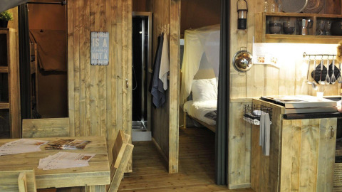 Binnenkant van de safaritent bij Lago Idro Glamping Boutique in Italië, met keuken en houten meubels.